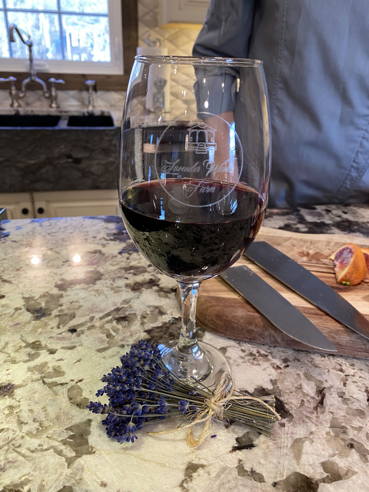 A glass of red wine beside a sprig of farm lavender
