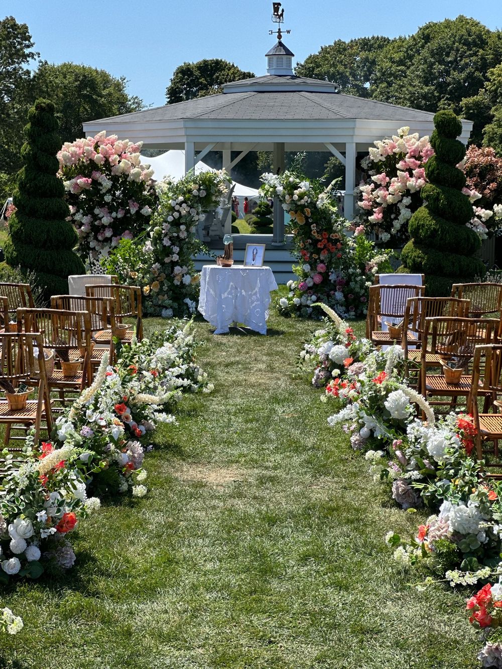 The gazebo dressed in flowers for a wedding ceremony, seen from the aisle