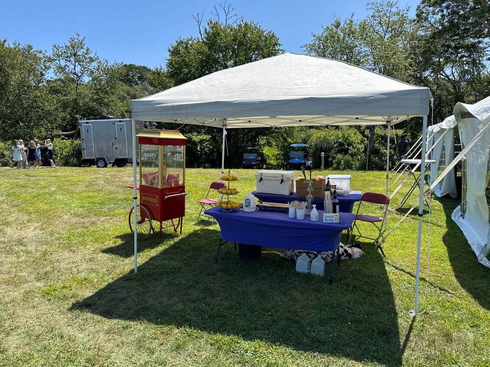 The popcorn cart and lemonade stand set up under a canopy at a wedding